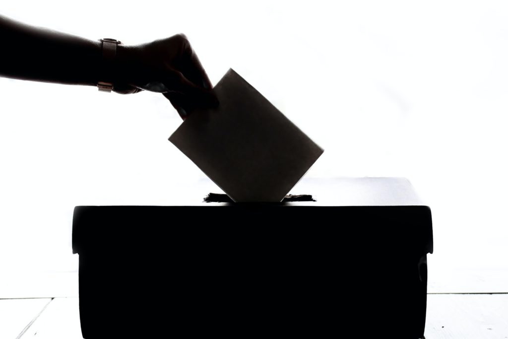 Eine Hand gibt einen Wahlumschlag in eine Wahlurne