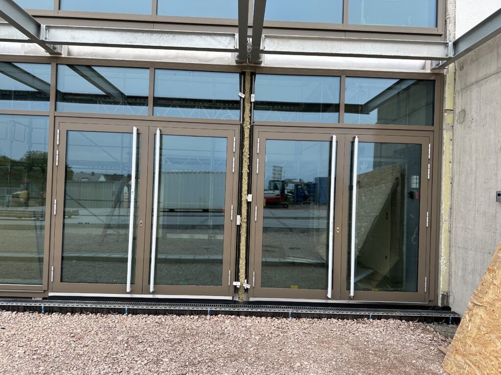 die neue Außentür zum Foyer/Mehrzweckraum. Rahmen in Antrazith Metallic, darin Glas.