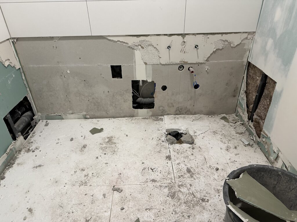 Ein Toilettenraum (für Kenner: eine barrierefreie Toilette) im Rückbau. Am Boden noch der Styroporuntergrund. Die Wand ist halb zurückgebaut.