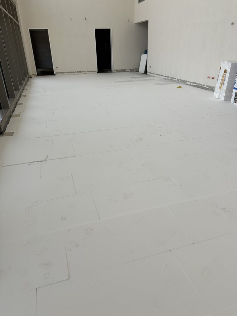 Ein Raum bedeckt mit weißen Platten, darauf Fußspuren - das Foyer der Halle vor dem Wiedereinbau der Heizspiralen.