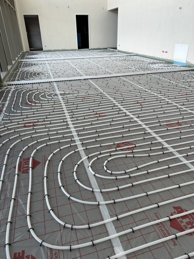 Ein Raum mit einer grauen Folie belegt, darauf weiße Schläuche in regelmäßigen Spiralen - das Foyer der Halle beim Wiederaufbau