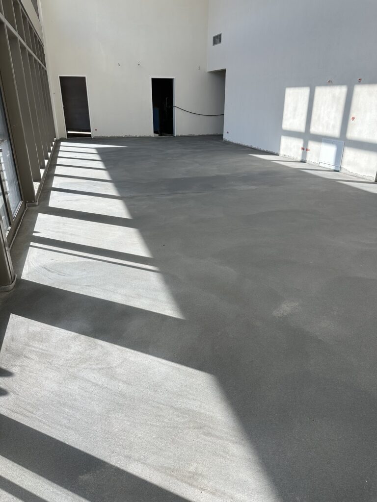 Ein Raum mit einem grauen Boden - Das Foyer der Halle mit wiederhergestelltem Estrich.